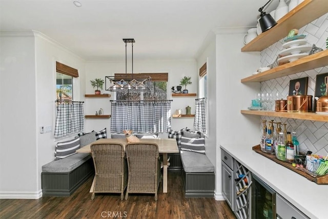 dining space with ornamental molding, a bar, beverage cooler, and dark wood-style floors