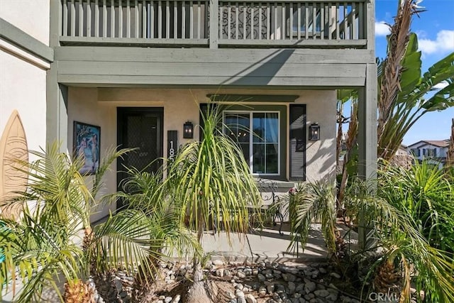 entrance to property with a balcony and stucco siding