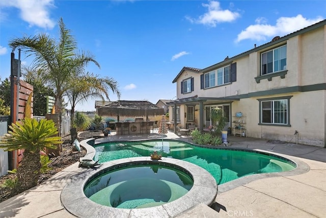 view of pool with a patio area, a pool with connected hot tub, outdoor dry bar, and fence