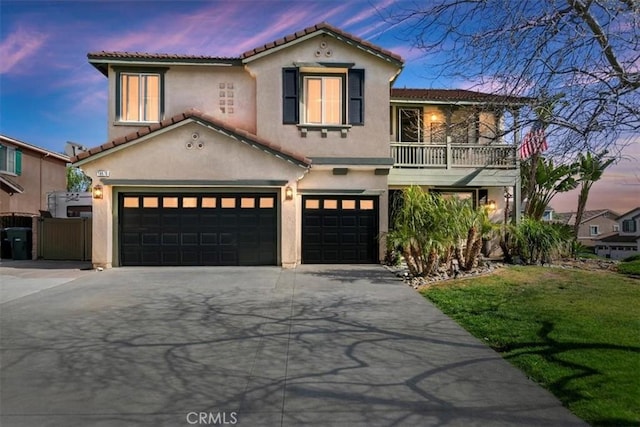 mediterranean / spanish house featuring an attached garage, stucco siding, a balcony, and concrete driveway