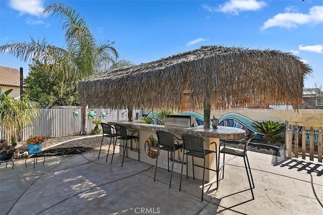 view of patio / terrace featuring a fenced backyard, outdoor wet bar, and area for grilling