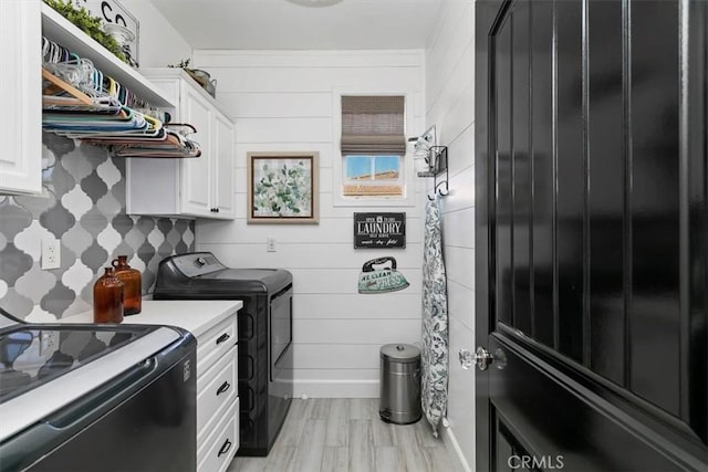 laundry room featuring light wood finished floors, washer and clothes dryer, and cabinet space