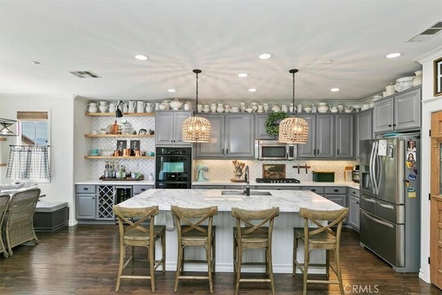 kitchen with appliances with stainless steel finishes, a sink, gray cabinetry, and visible vents