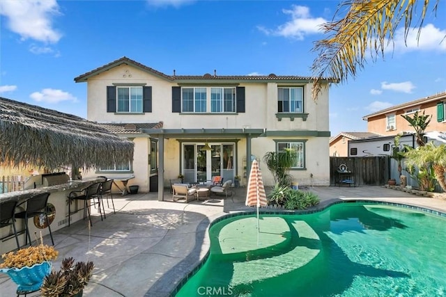 rear view of property with a patio area, a tile roof, fence, outdoor dry bar, and stucco siding