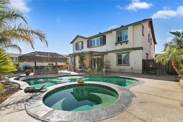 view of swimming pool featuring outdoor dry bar, a patio area, a pool with connected hot tub, and fence