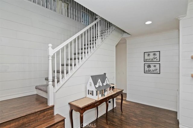 stairway with ornamental molding, recessed lighting, wood finished floors, wood walls, and baseboards