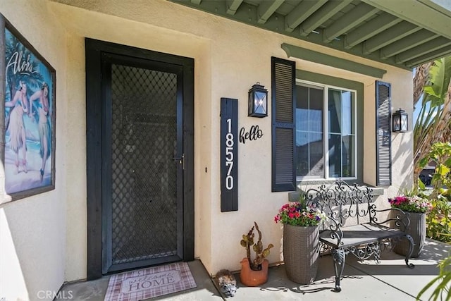 property entrance with covered porch and stucco siding