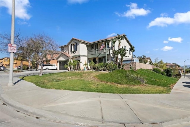 view of front of home featuring a residential view, stucco siding, a balcony, driveway, and a front lawn