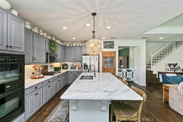 kitchen with a sink, gray cabinets, dark wood-style floors, and stainless steel appliances