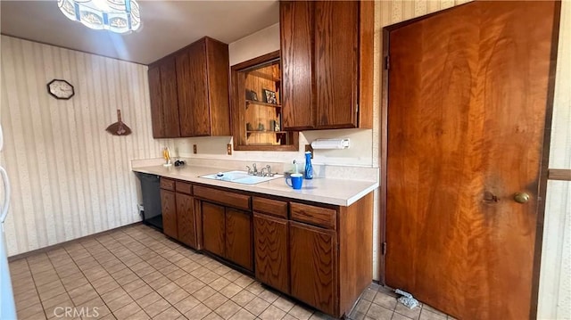kitchen featuring a sink, wallpapered walls, dishwasher, light countertops, and light tile patterned floors