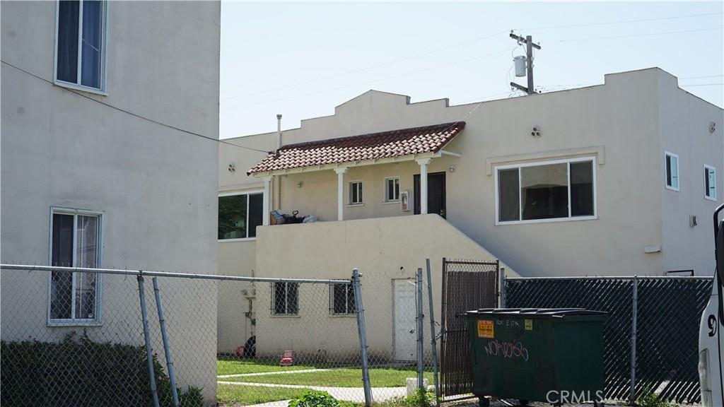 rear view of property with stucco siding, fence, and a gate
