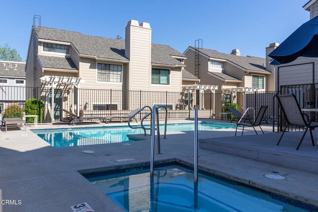 community pool featuring a community hot tub, a residential view, fence, and a patio