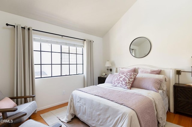 bedroom featuring wood finished floors, baseboards, and vaulted ceiling