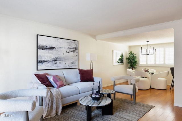 living area with crown molding, light wood-style flooring, a notable chandelier, and a healthy amount of sunlight