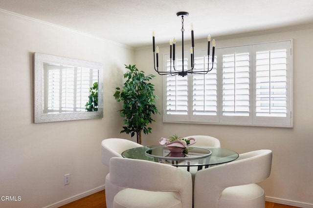 dining space featuring ornamental molding, baseboards, an inviting chandelier, and wood finished floors