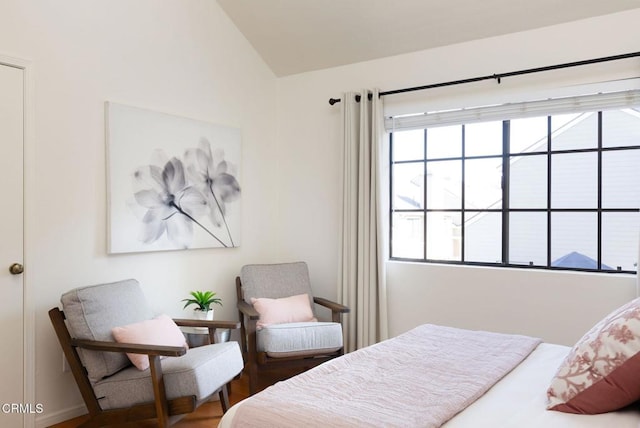 bedroom with wood finished floors and lofted ceiling