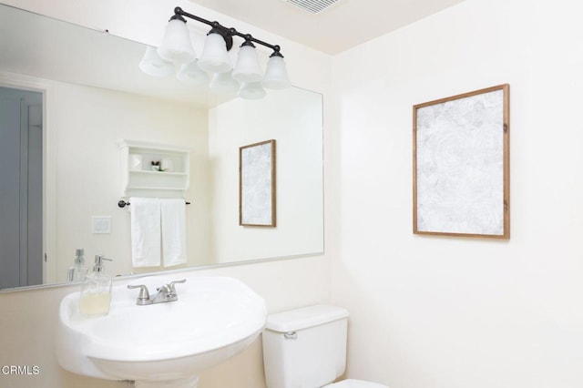 half bathroom with visible vents, a sink, and toilet