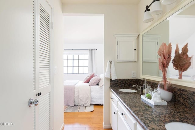 ensuite bathroom with a sink, ensuite bathroom, double vanity, and wood finished floors