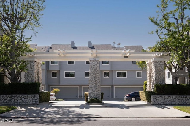 exterior space featuring an attached garage, a chimney, and concrete driveway