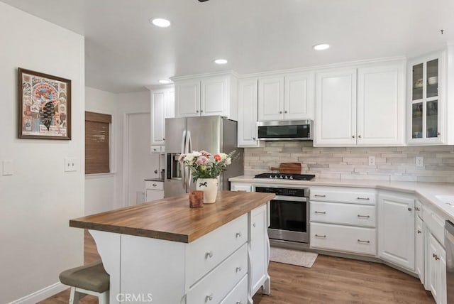 kitchen with white cabinetry, appliances with stainless steel finishes, decorative backsplash, and butcher block counters