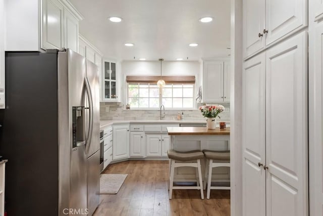 kitchen with stainless steel refrigerator with ice dispenser, white cabinetry, butcher block counters, and glass insert cabinets