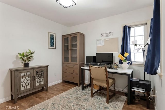 home office featuring baseboards, wood finished floors, and a wealth of natural light