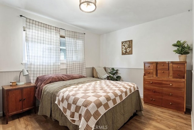 bedroom with wainscoting and light wood finished floors