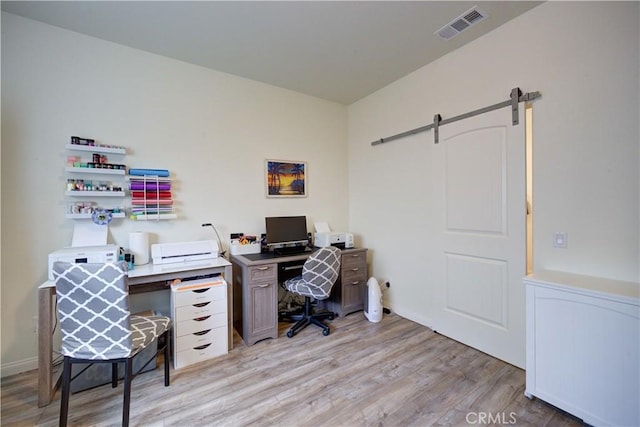 office space with a barn door, light wood finished floors, and baseboards