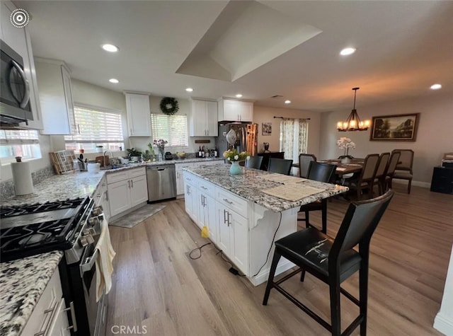 2145 Grand Ave, San Bernardino, CA 92407 - kitchen with stainless steel appliances, a breakfast bar area, a chandelier, white cabinets, and recessed lighting