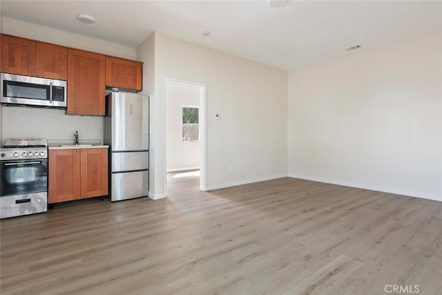 8856 Fullbright Ave, Winnetka, CA 91306 - kitchen featuring light wood-type flooring, stainless steel appliances, a sink, and brown cabinetry