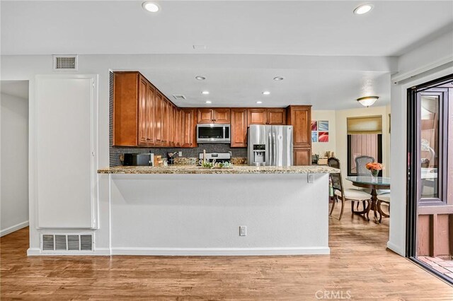 kitchen featuring brown cabinets, stainless steel appliances, visible vents, and decorative backsplash