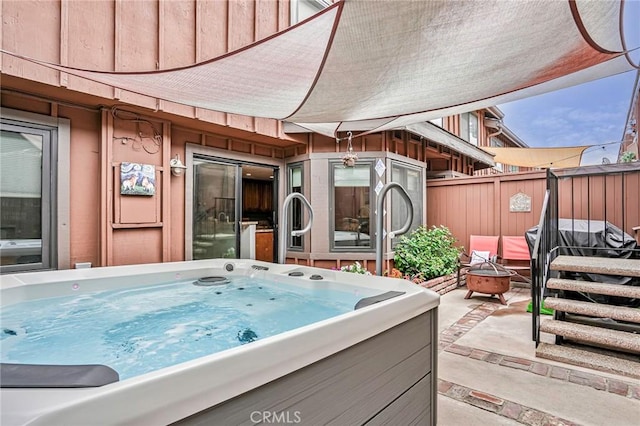 exterior space featuring a hot tub, fence, and an outdoor fire pit