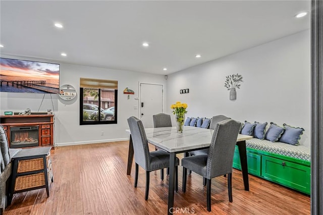 dining space with a glass covered fireplace, baseboards, recessed lighting, and wood finished floors