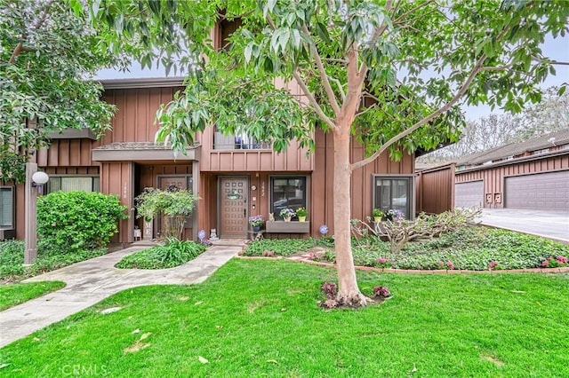 view of property featuring a garage, board and batten siding, and a front yard