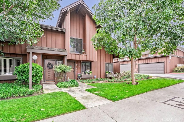 townhome / multi-family property with board and batten siding, a front yard, and a garage