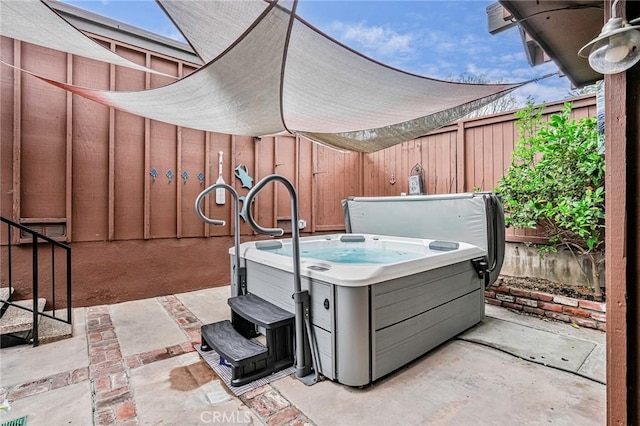 view of patio / terrace with a hot tub and fence