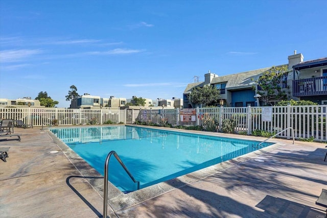 community pool featuring fence, a residential view, and a patio area