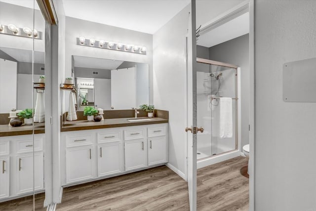 full bath featuring vanity, wood finished floors, toilet, and a shower stall