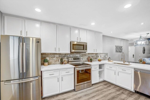 kitchen featuring decorative backsplash, light wood-type flooring, a sink, stainless steel appliances, and white cabinetry