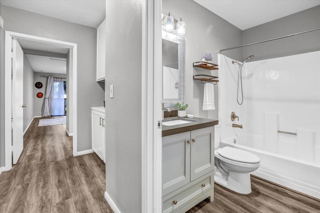 bathroom with vanity, toilet, baseboards, wood finished floors, and shower / bathing tub combination