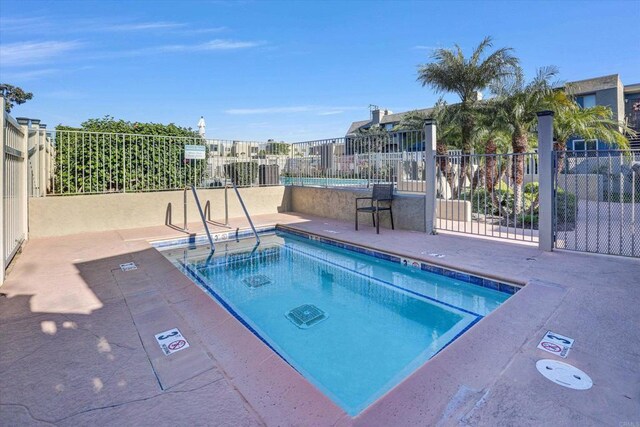 view of pool featuring a hot tub and fence