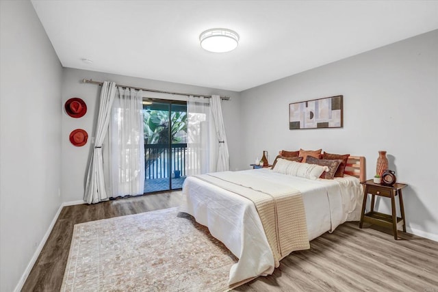 bedroom with baseboards, access to exterior, and wood finished floors