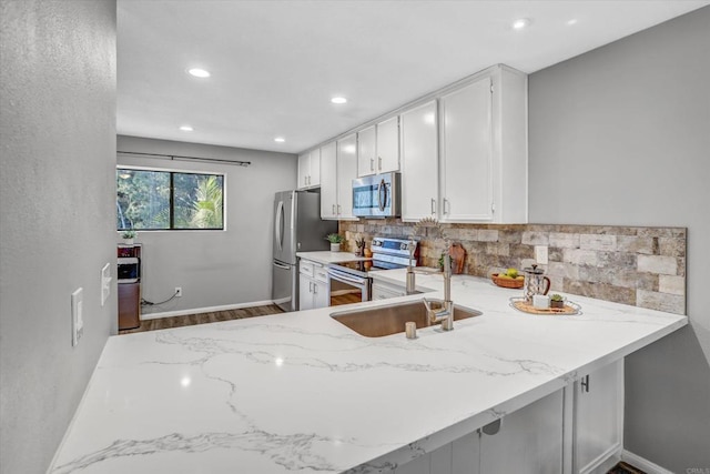 kitchen featuring decorative backsplash, a sink, appliances with stainless steel finishes, and light stone countertops