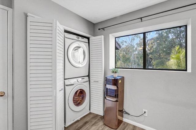 washroom featuring baseboards, stacked washer and dryer, laundry area, and wood finished floors