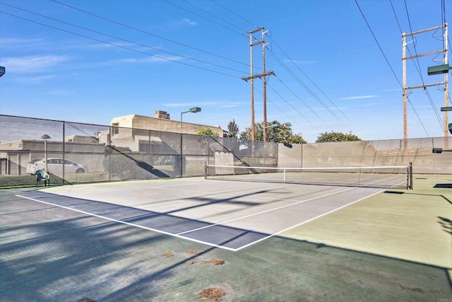 view of tennis court featuring community basketball court and fence
