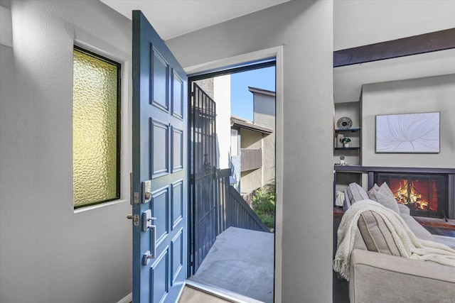 doorway featuring a lit fireplace, built in features, and light wood finished floors