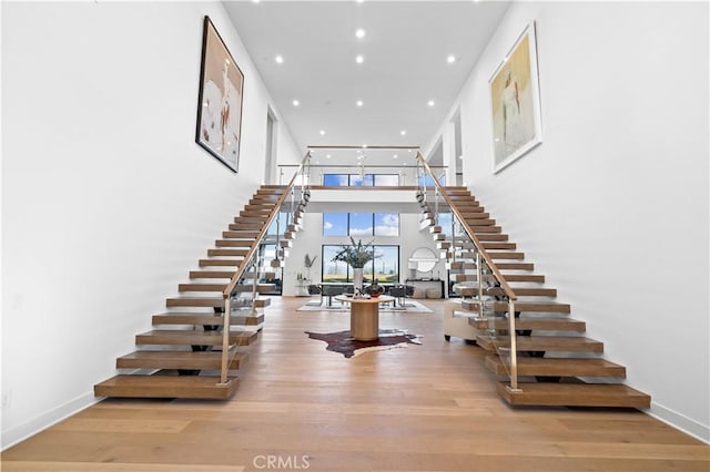 stairway with recessed lighting, wood finished floors, and baseboards