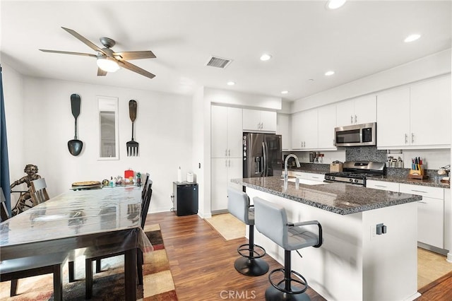 45477 Calle Cirros, Temecula, CA 92592 - kitchen with appliances with stainless steel finishes, a breakfast bar area, a sink, light wood-type flooring, and a kitchen island with sink