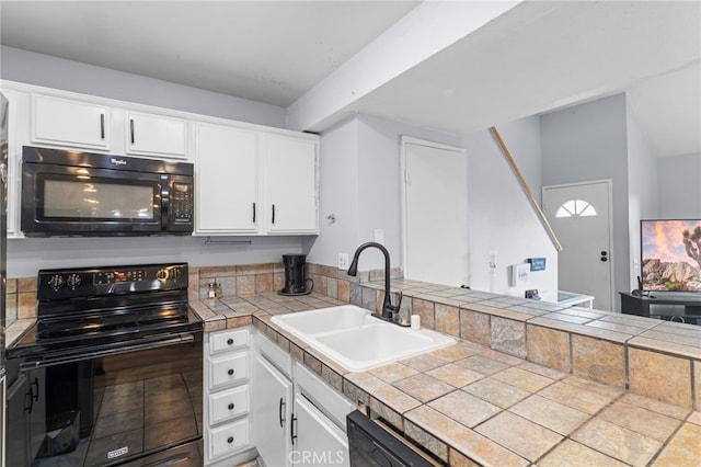 kitchen featuring a peninsula, a sink, black appliances, and white cabinetry