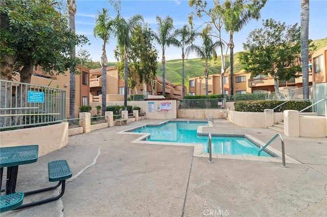 community pool with a residential view, fence, and a patio